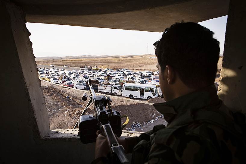 Иракский военный перед беженцами из Мосула в окрестностях Эрбиля