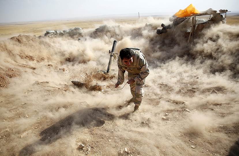 Боец курдского ополчения пешмерга запускает мину в сторону населенного пункта Зумар