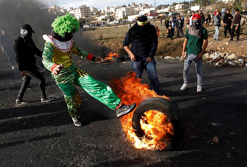 Бейт-Эль, Западный берег реки Иордан. Палестинец пинает горящую шину во время столкновений с израильскими военными