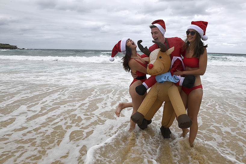 Сидней, Австралия. Элинор Хэдли из Уэльса (слева), Глен Хокинс из Англии (в центре) и Джоди Страхан из Шотландии (справа) в этом году решили встретить Рождество на пляже 