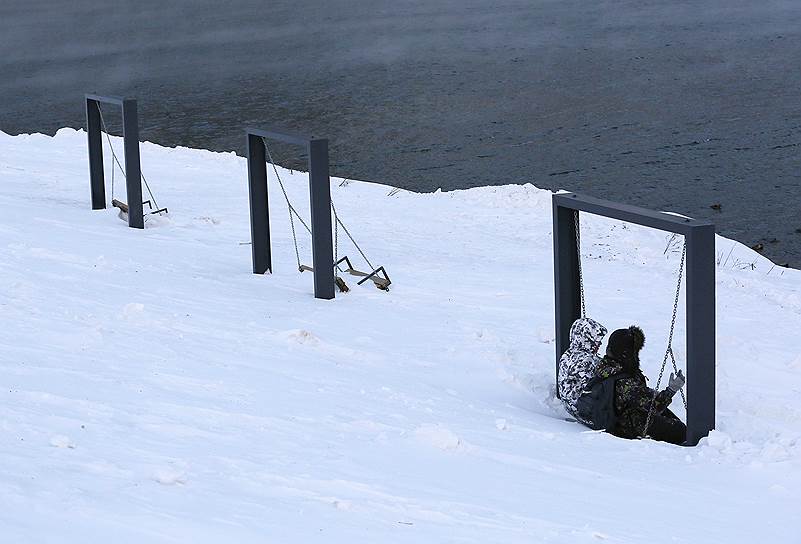 Дивногорск, Россия. Дети сидят на засыпанных снегом качелях на берегу Енисея
