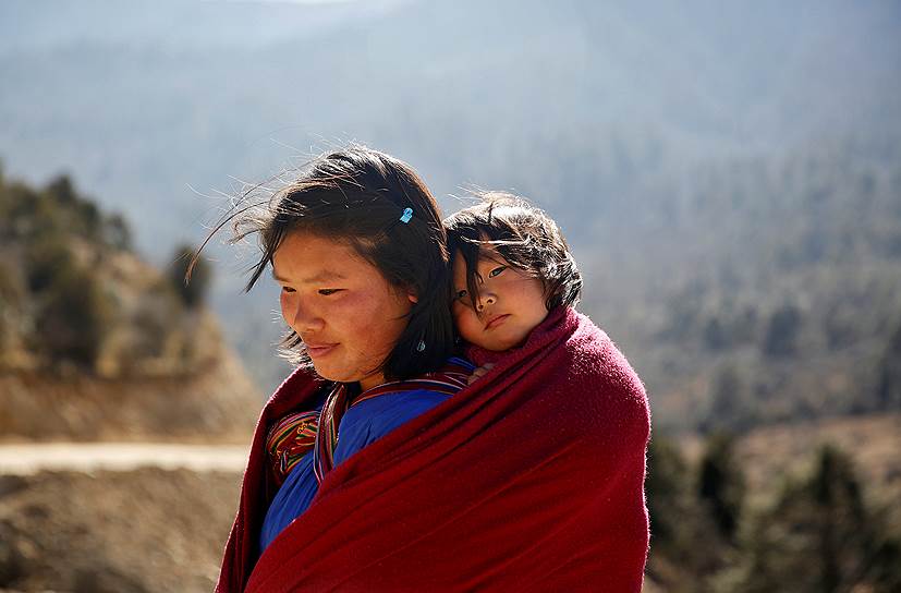 Пунакха, Бутан. Местная жительница несет на спине свою дочь