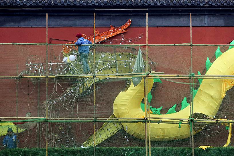 Нанкин, Китай. Рабочие устанавливают фонарь в форме дракона в преддверии Китайского Нового года