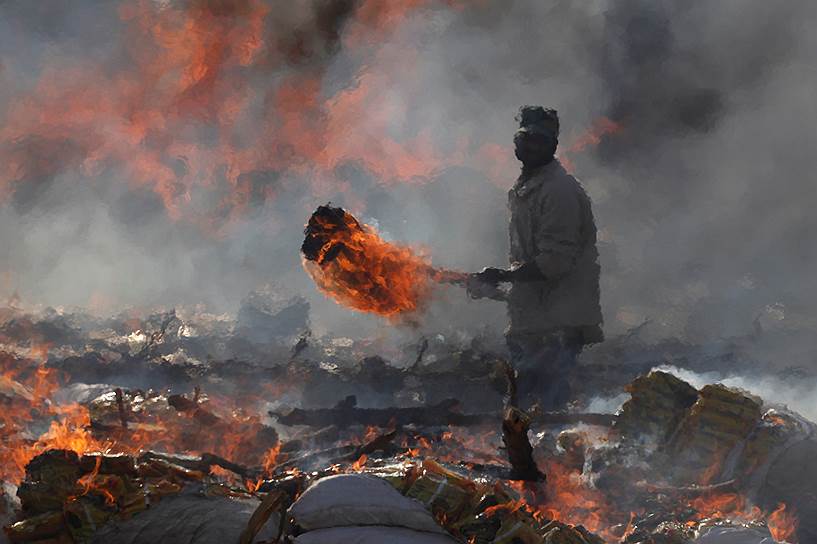 Карачи, Пакистан. Сотрудник таможни сжигает контрабандные товары в Международный день таможенника