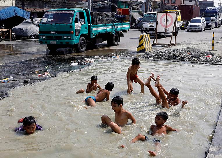 Манила, Филиппины. Местные мальчики купаются в яме 