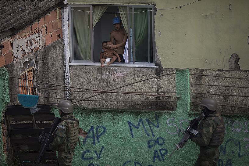 Рио-де-Жанейро, Бразилия. Местный житель прячет лицо ребенка во время рейда полиции в неблагополучном районе Сидаде-де-Деуш