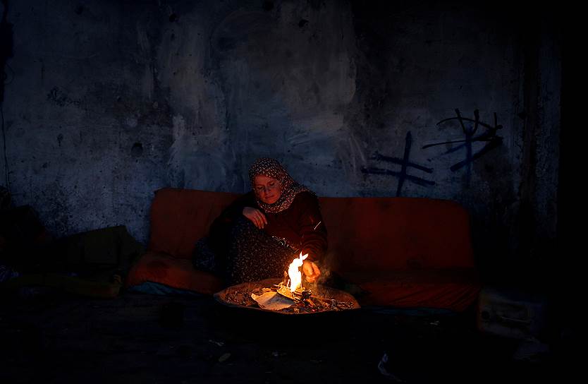 Сектор Газа, Палестина. Местная жительница греется у себя дома