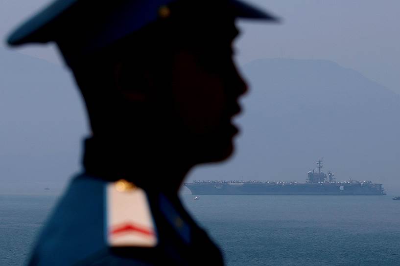 Дананг, Вьетнам. Военный дежурит в порту на фоне американского авианосца «Карл Винсон»