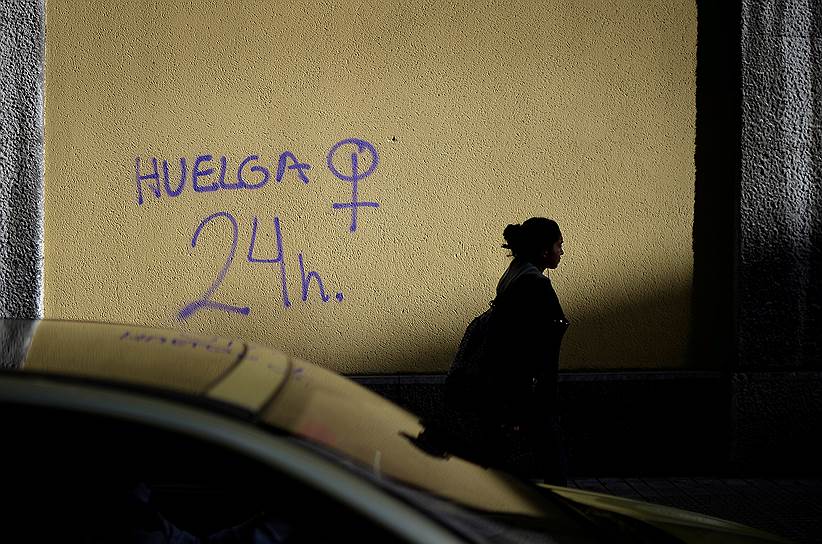 Бильбао, Испания. Местная жительница проходит мимо здания с граффити с призывом к 24-часовой забастовке в честь Международного женского дня