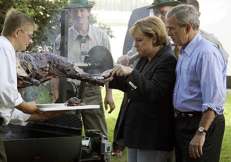 Июль 2006 года. Ангела Меркель отрезает кусок жареной свинины для президента США Джорджа Буша-младшего (2001—2009) во время барбекю с жителями деревни Тринвиллершаген на северо-востоке Германии