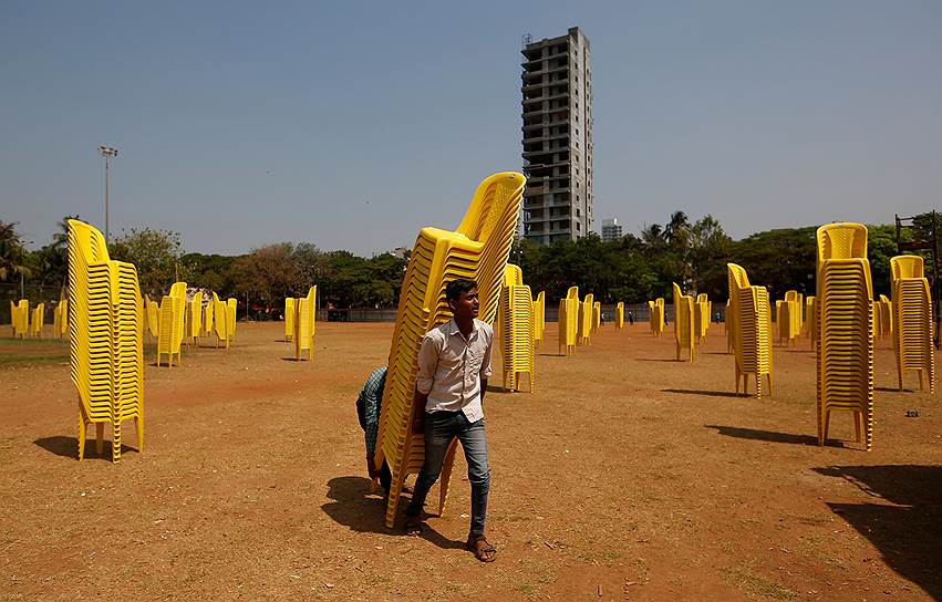 Мумбаи, Индия. Рабочий несет пластиковые стулья перед собранием одной из политических партий 