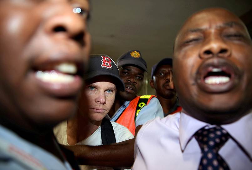 Йоханнесбург, ЮАР. Полиция аэропорта сопровождает игрока в крикет Стива Смита
