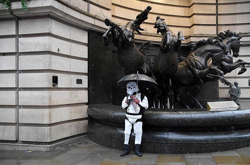 Лондон, Великобритания. Местный житель в костюме штурмовика из фильма «Звездные войны» спасается от дождя
