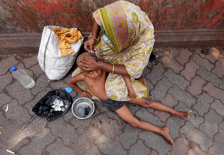 Калькутта, Индия. Местная жительница с ребенком сидит на земле рядом с рыночной площадью