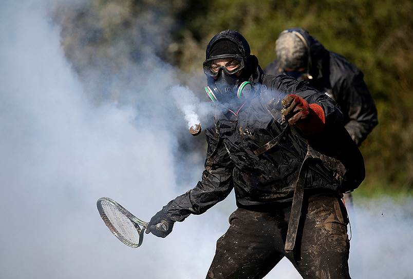 Нотр-Дам-де-Ланд, Франция. Протестующий против строительства аэропорта использует теннисную ракетку, чтобы отбивать шашки со слезоточивым газом