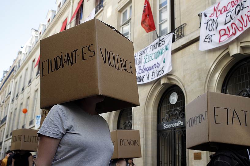Париж, Франция. Студенты с коробками на голове, на которых написано &quot;Борьба, студенты, насилие, долг, движение, государство&quot;, выступают перед заблокированным входом в Институт политических исследований