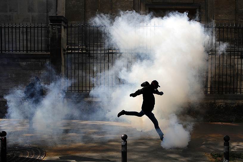 Париж, Франция. Активист отбрасывает дымовую шашку, запущенную полицией, на акции протеста против железнодорожной реформы