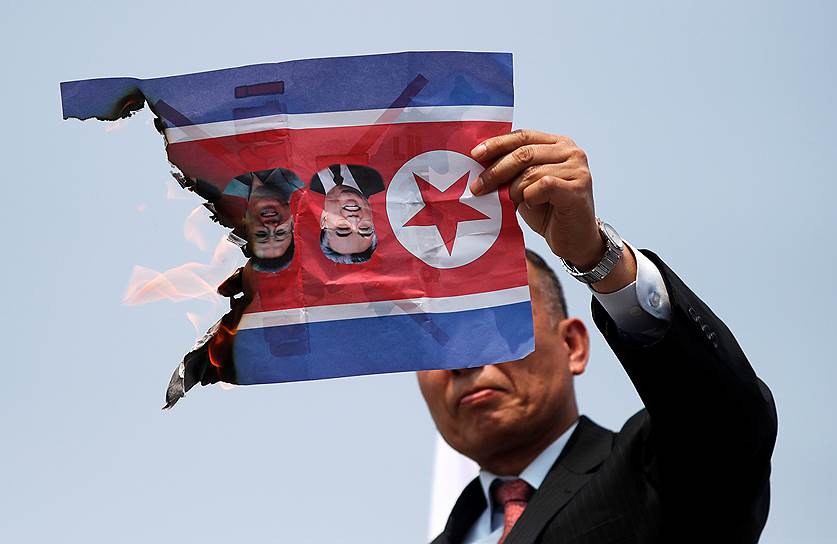 В районе, где проходил саммит, прошла также демонстрация против встречи лидеров двух стран&lt;br>На фото: мужчина сжигает флаг КНДР с фотографиями Ким Ир Сена и Ким Чен Ира 