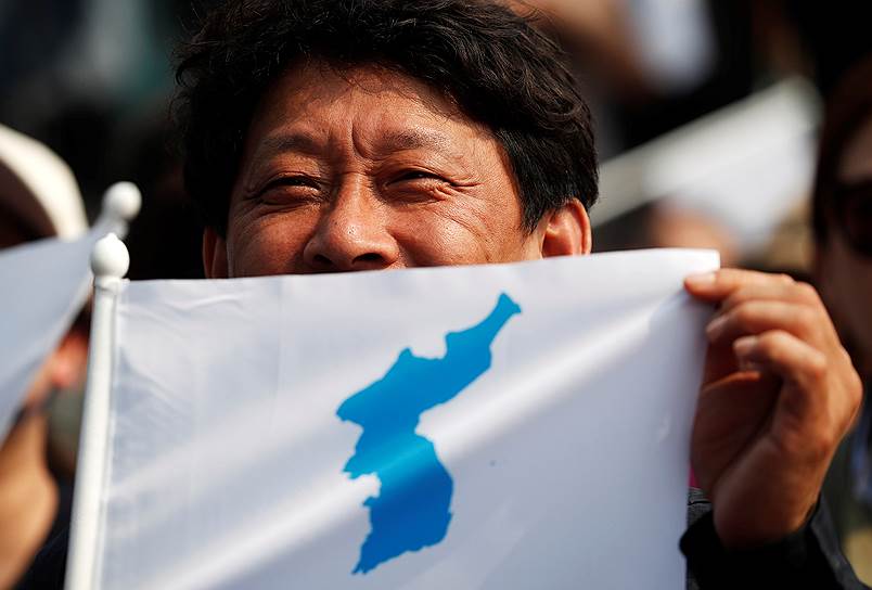 Мужчина с флагом объединения двух Корей на митинге в приграничном Пхаджу в Южной Корее