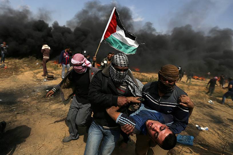 Сектор Газа. Палестинцы несут раненого во время столкновений с израильскими военными 