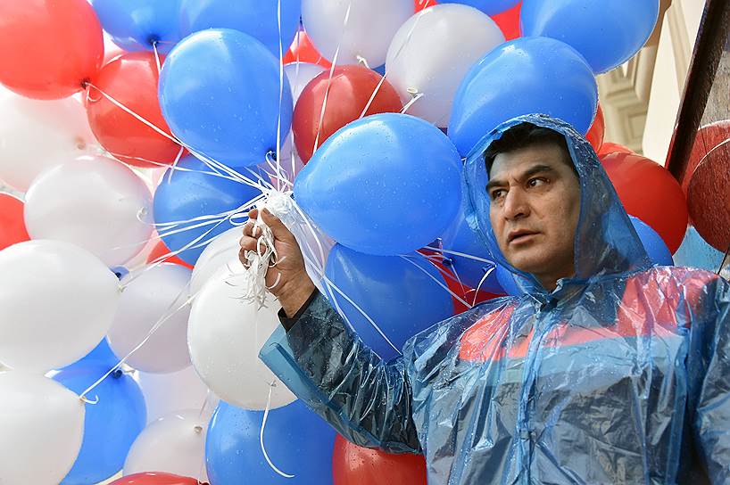Участник шествия на Красной площади держит в руках воздушные шары 