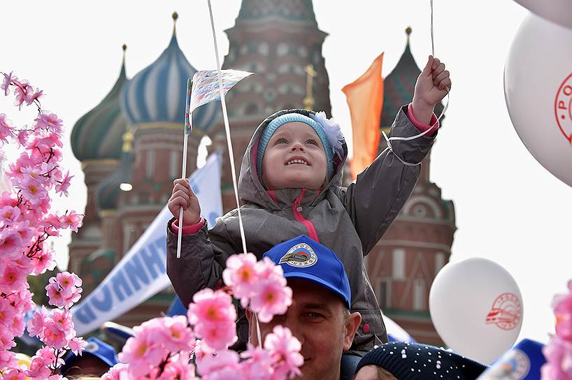 Ребенок держит в руках флажок во время первомайского шествия