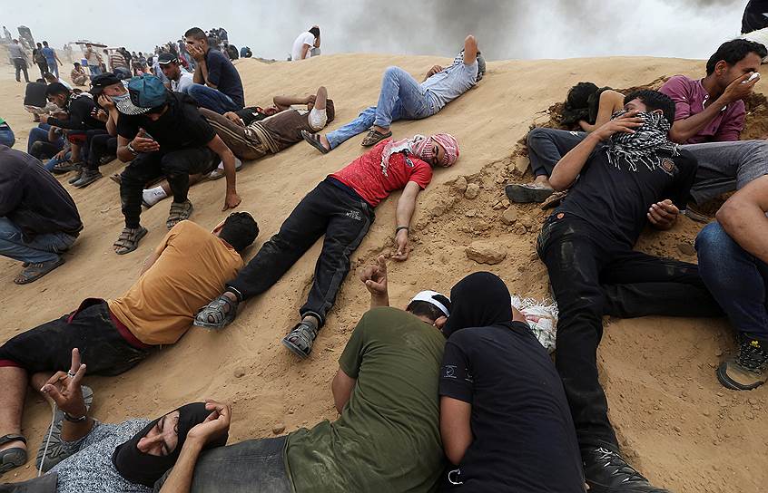 Сектор Газа. Палестинские протестующие лежат на песке после применения израильскими военными слезоточивого газа