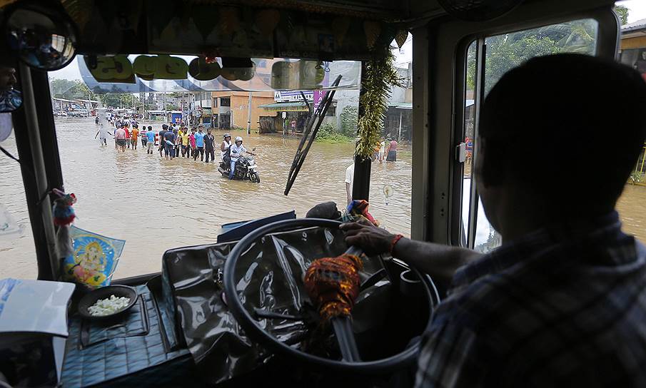Коломбо, Шри-Ланка. Водитель автобуса едет по затопленной дороге
