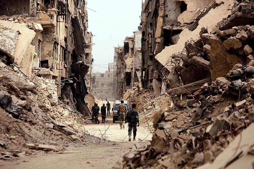 Дамаск, Сирия. Солдат идет мимо разрушенных домов в лагере палестинских беженцев 