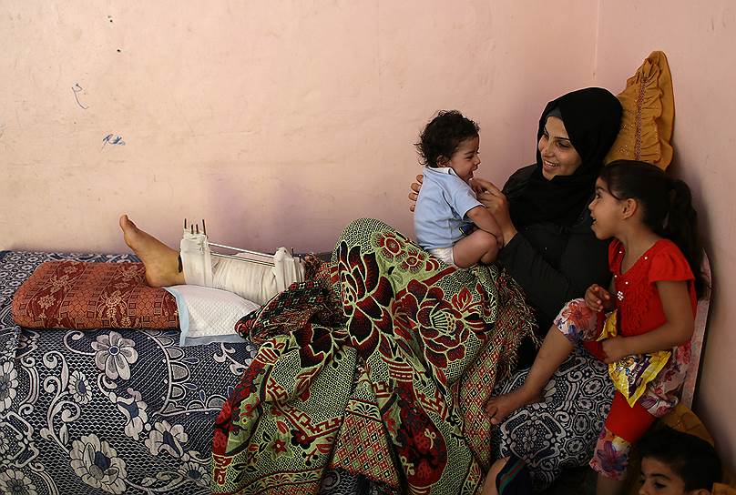 Сектор Газа, Палестина. Женщина, получившая ранение в столкновениях с израильскими военными, играет со своими детьми 