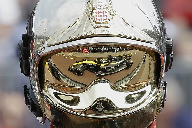 Монако. Болид немецкого автогонщика Нико Хюлькенберга отражается в шлемофоне пожарного во время свободных заездов перед Гран-при «Формулы-1» 