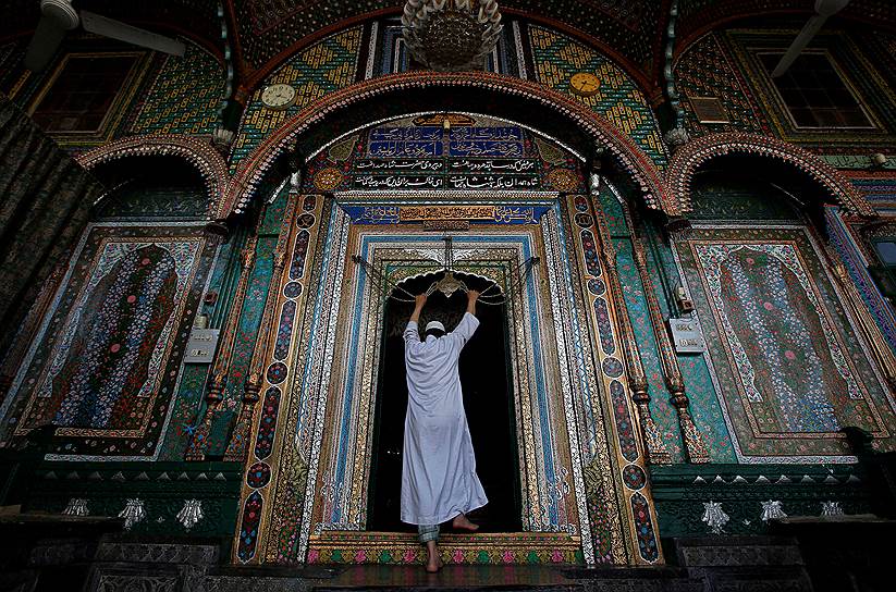Сринагар, Индия. Мусульманин молится у орнамента с цитатами из Корана в мечети