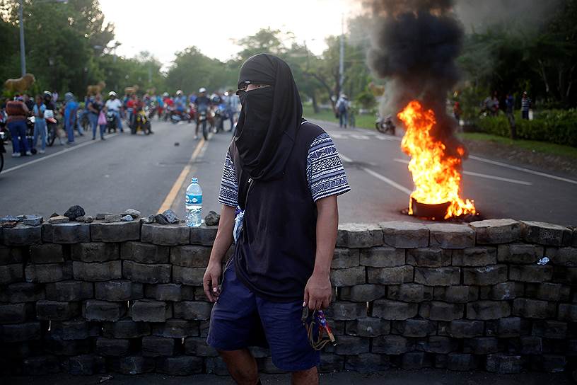 Участник антиправительственных выступлений в Никарагуа рядом с баррикадой, заблокировавшей Панамериканское шоссе