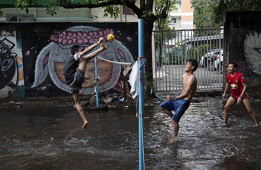 Бангкок, Таиланд. Рабочие мигранты во время игры на залитом дождевой водой поле