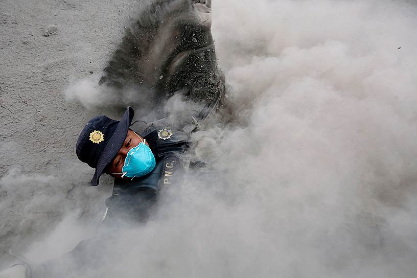 Эскуинтла, Гватемала. Полицейский окутан дымом вулкана Фуэго 
