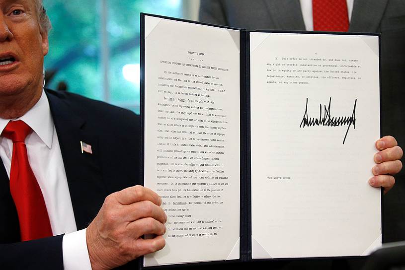 Президент США Дональд Трамп держит в руках подписанный им миграционный указ
