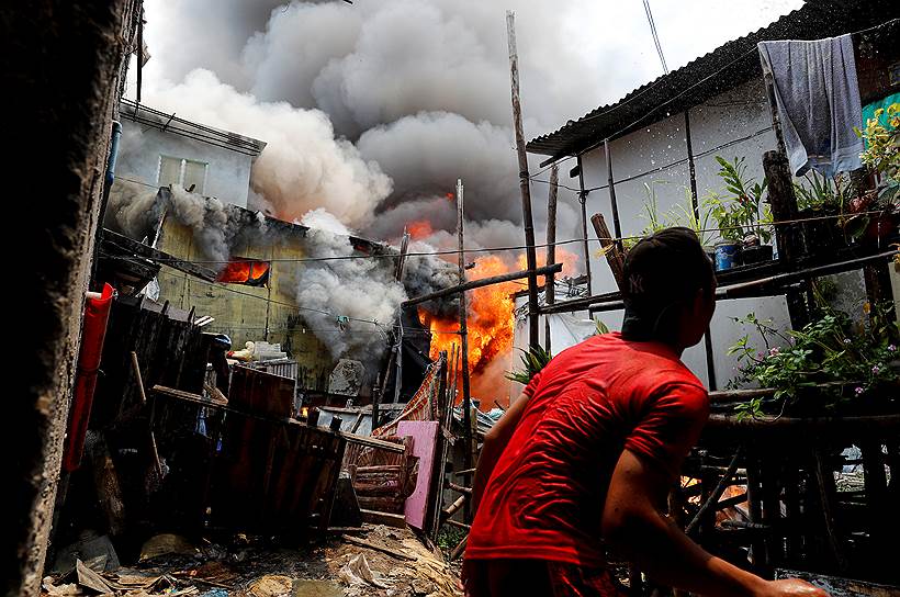 Мунтинлупа, Филиппины. Местный житель тушит свой дом