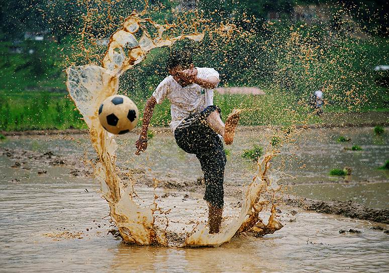 Лалитпур, Непал. Мужчина играет в футбол на рисовом поле в праздник Асар Пандра — наиболее благоприятный день для посадки риса 
