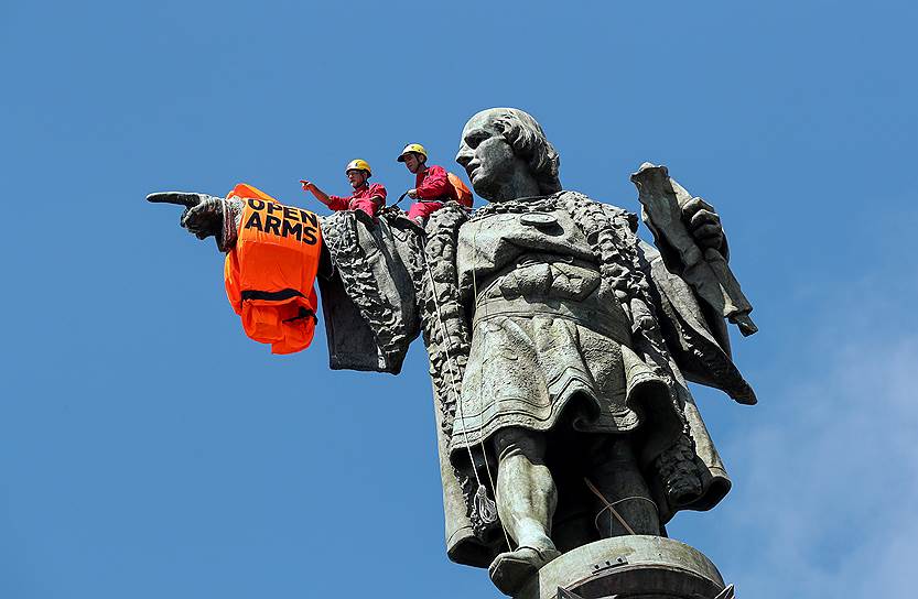 Барселона, Испания. Активисты благотворительной организации Proactiva Open Arms надели спасательный жилет на статую Христофора Колумба после прибытия в городской порт лодки с мигрантами из Ливии
