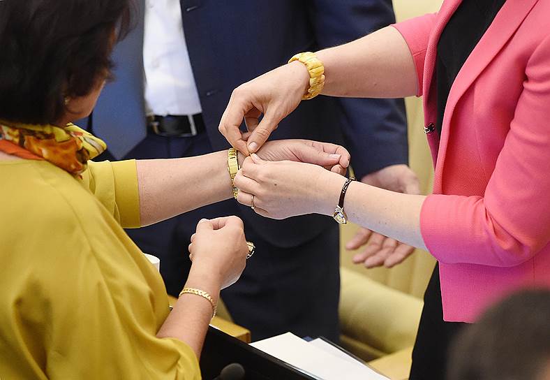Депутаты примеряют браслеты перед началом пленарного заседания 5 июля