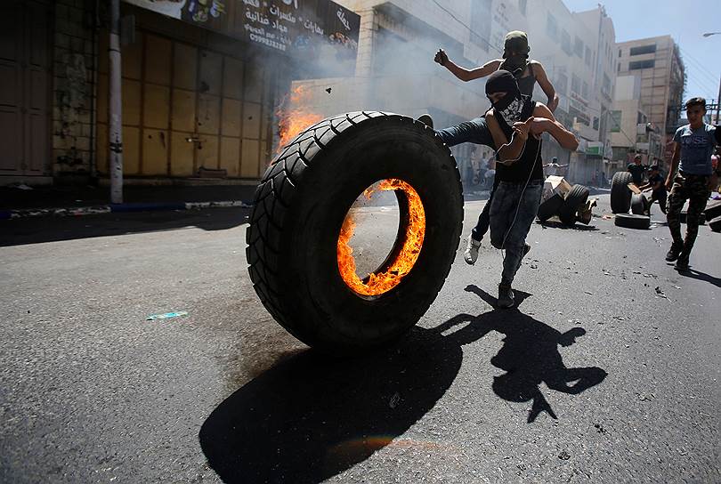 Хеврон, Западный берег реки Иордан. Протестующие палестинцы катят горящую шину