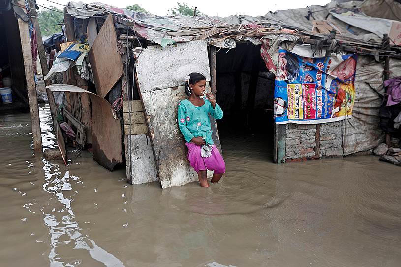 Нью-Дели, Индия. Девочка чистит зубы около своей хижины в затопленных трущобах