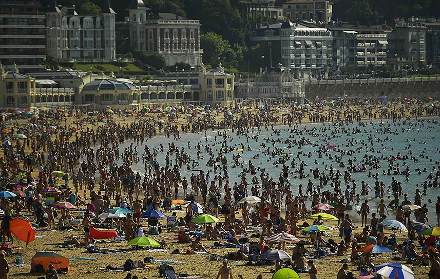 Люди толпятся на пляже в испанском городе Сан-Себастьян