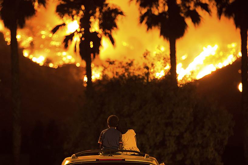 Озеро Элзинор, штат Калифорния, США. Дети сидят на крыше машины и наблюдают за лесным пожаром