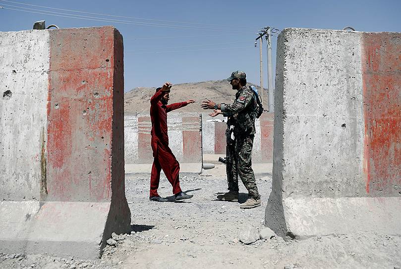 Афганистан. Военнослужащий афганской армии досматривает мужчину на контрольно-пропускном пункте на шоссе Газни-Кабул