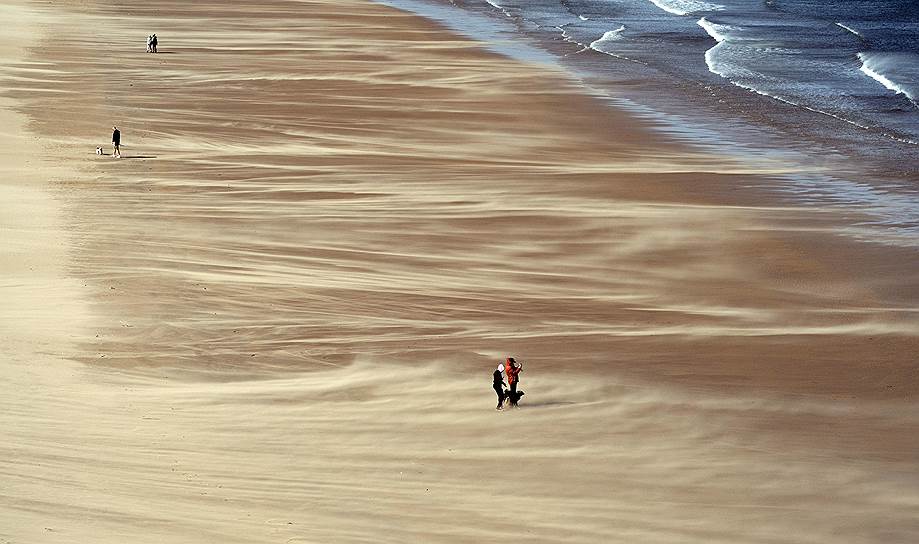 Тайнмут, Англия. Местные жители гуляют по пляжу  