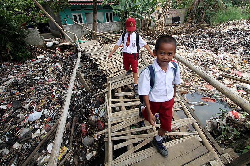 Богор, Индонезия. Школьники переходят мост над рекой Чиливунг