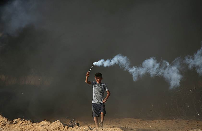 Сектор Газа. Пелестинский мальчик держит в руках выпущенную израильскими военными дымовую шашку