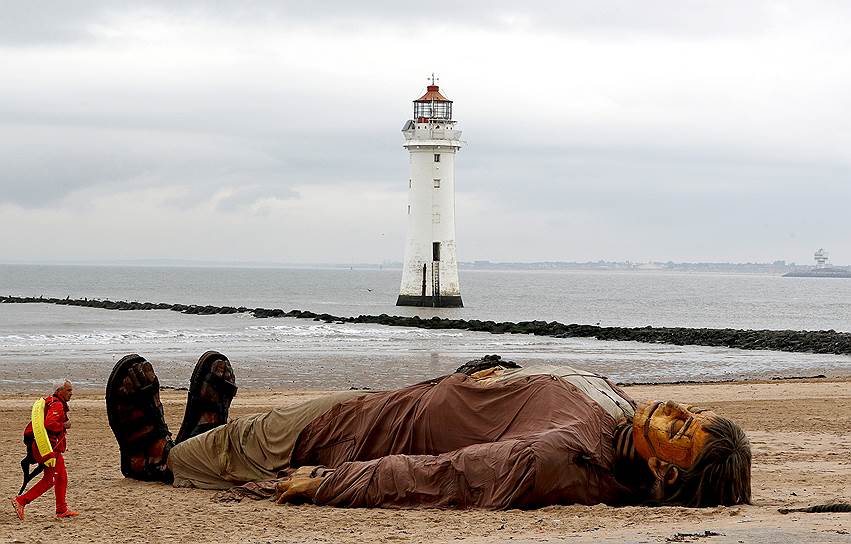 Нью-Брайтон, Англия. Спасатель идет рядом с гигантской куклой