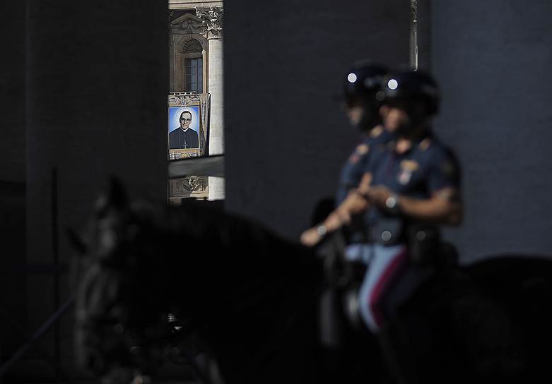 Площадь Святого Петра, Ватикан. Полицейские проезжают мимо портрета архиепископа Оскара Ромеро, которого в воскресенье папа римский Франциск собирается объявить святым